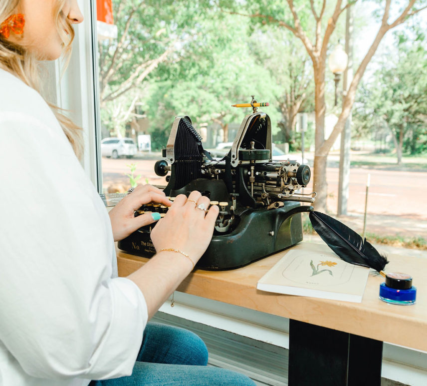 Girl typing on Typewriter in coffee shop